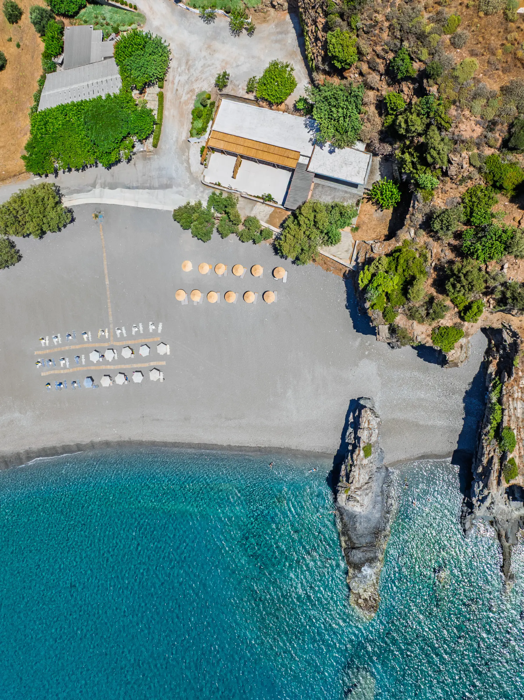Straight down on the sea stack at the east end of Korakas, the umbrella rows and the house behind the beach